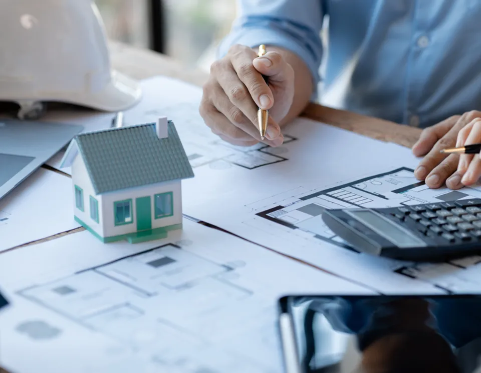 Firma di documenti tecnici con modellino di casa su planimetria