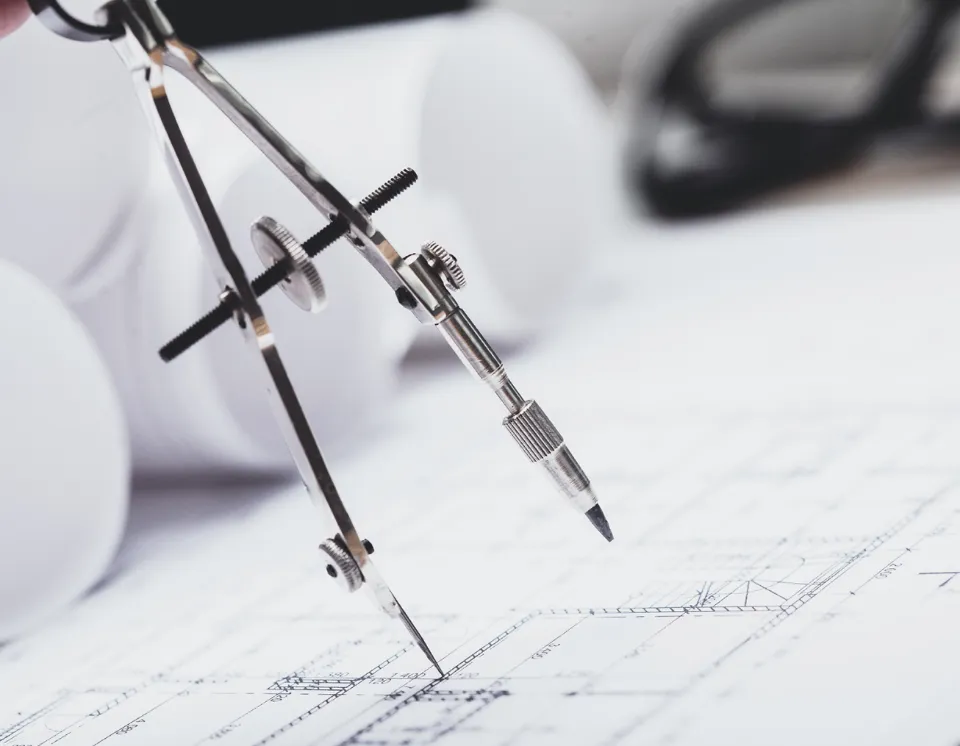 Compasso e strumenti tecnici su disegno architettonico